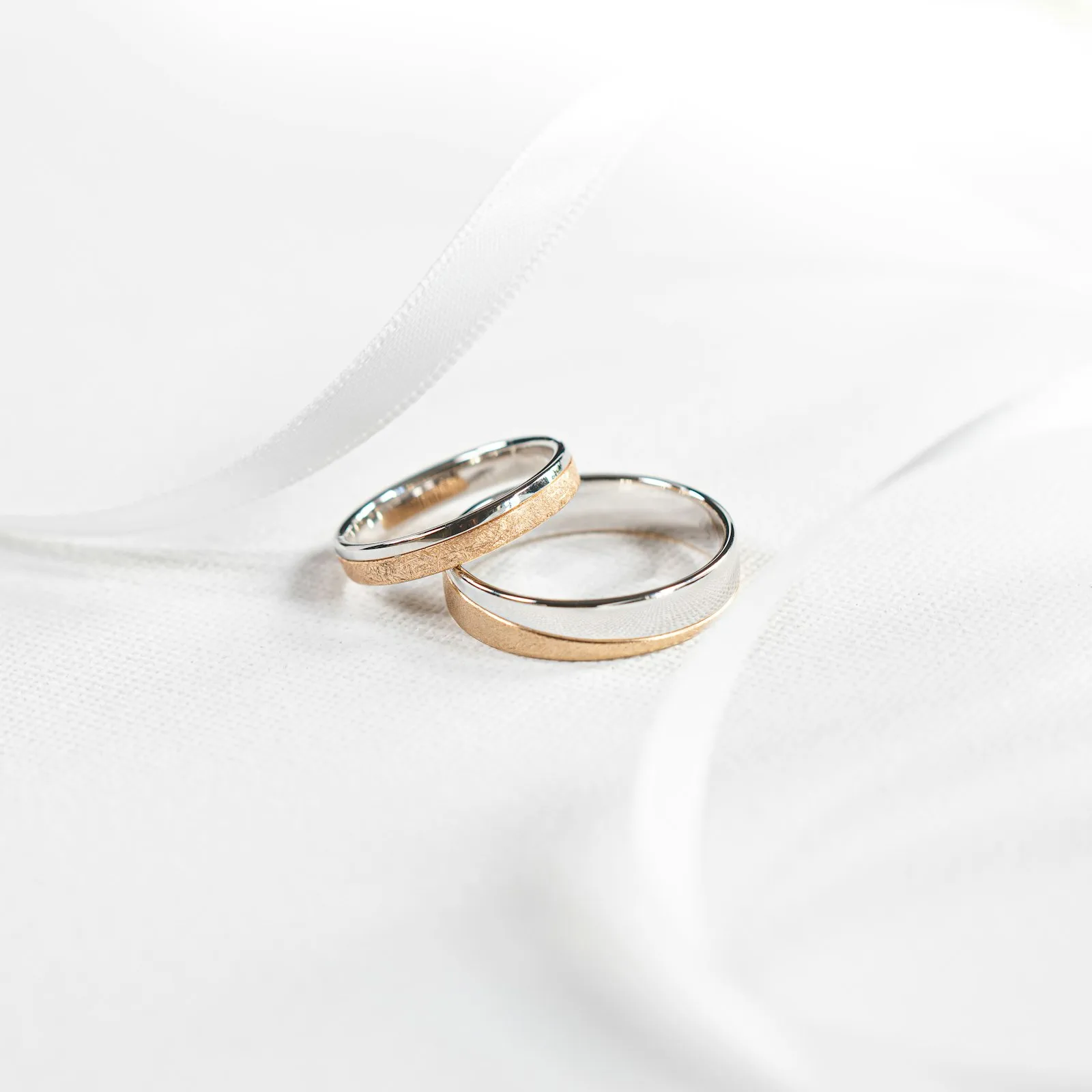 Cincin kawin dua warna di atas sutra putih