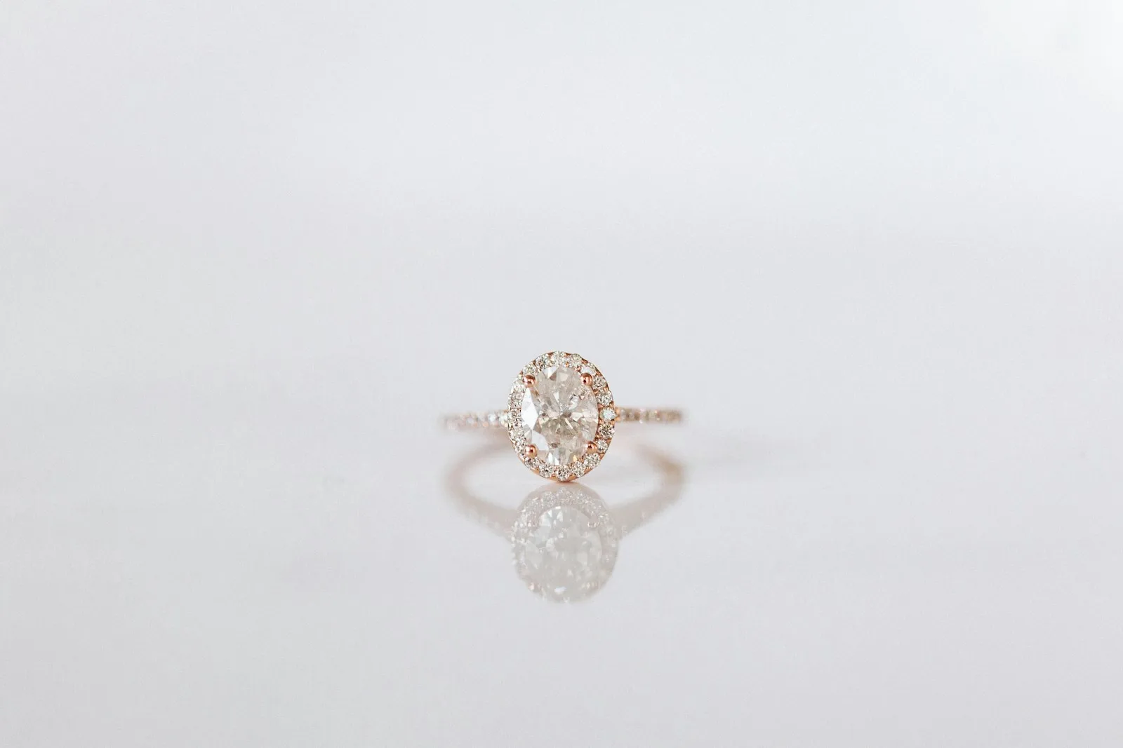 Cincin solitaire berlian oval emas mawar di atas permukaan putih