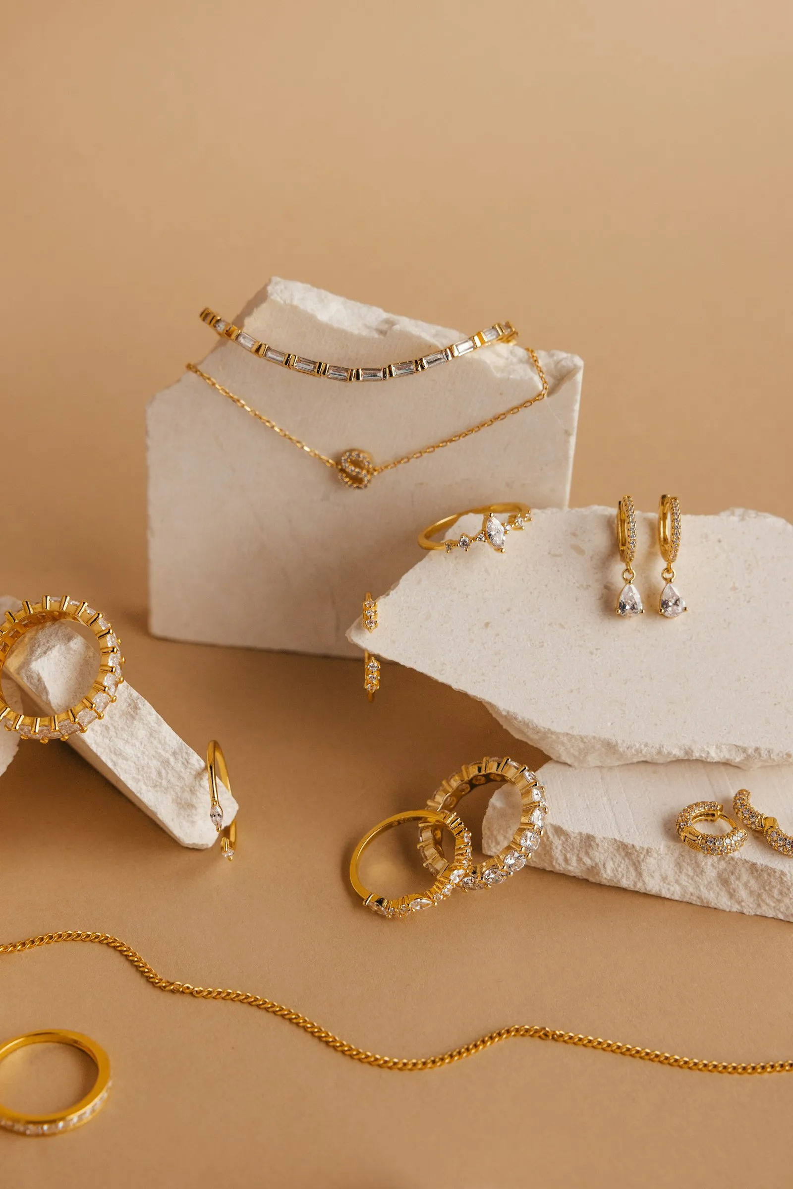 Kalung, cincin, dan anting emas ditata di atas batu putih