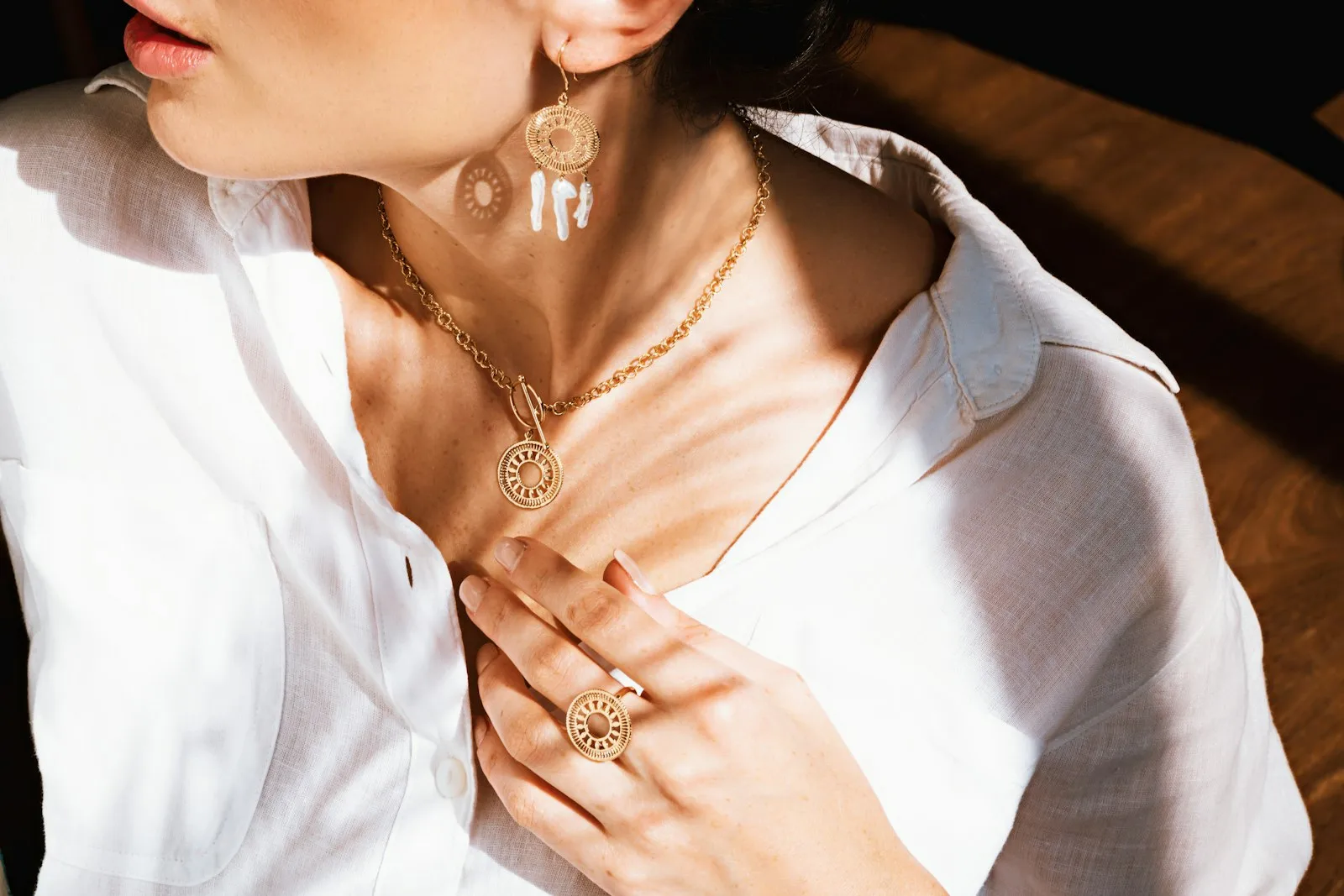 Wanita berkemeja putih mengenakan kalung dan anting emas berlapis